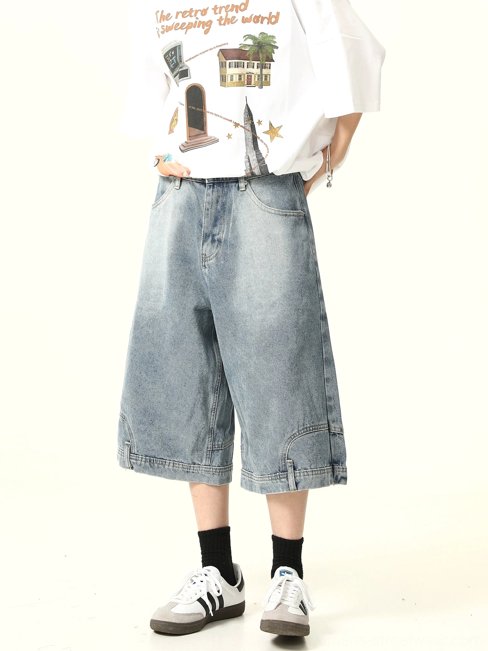 Slight front side view of high-rise washed denim culotte shorts with classic pocket layout, wide cropped legs, graphic T-shirt, and retro sneakers