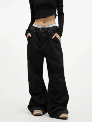 Front full body view of high waist black baggy denim jeans with contrast stitching and ultra wide legs styled with a cropped top
