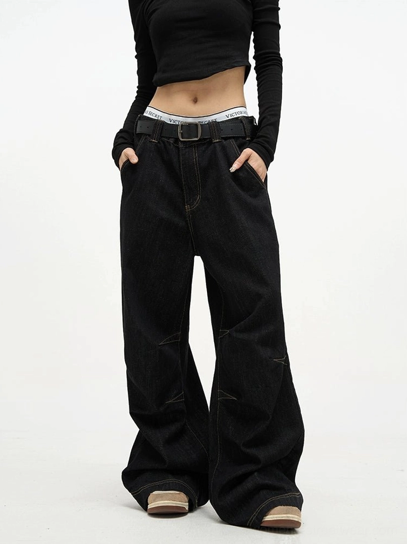 Front full body view of high waist black baggy denim jeans with contrast stitching and ultra wide legs styled with a cropped top
