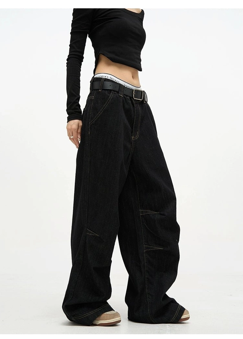 Side view of high waist black baggy denim jeans with contrast stitching styled with a fitted cropped black top