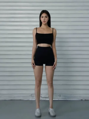 Black high-waist breathable cycling shorts shown from the front with a sleek fitted silhouette styled with a black camisole and white sneakers