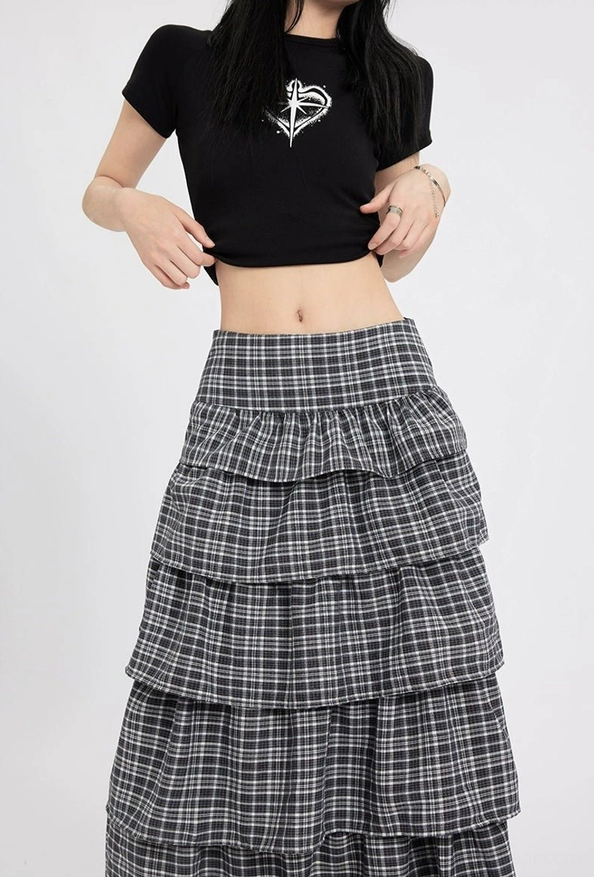 Close up waist view showing the high waisted construction and layered ruffle details of a dark plaid maxi skirt