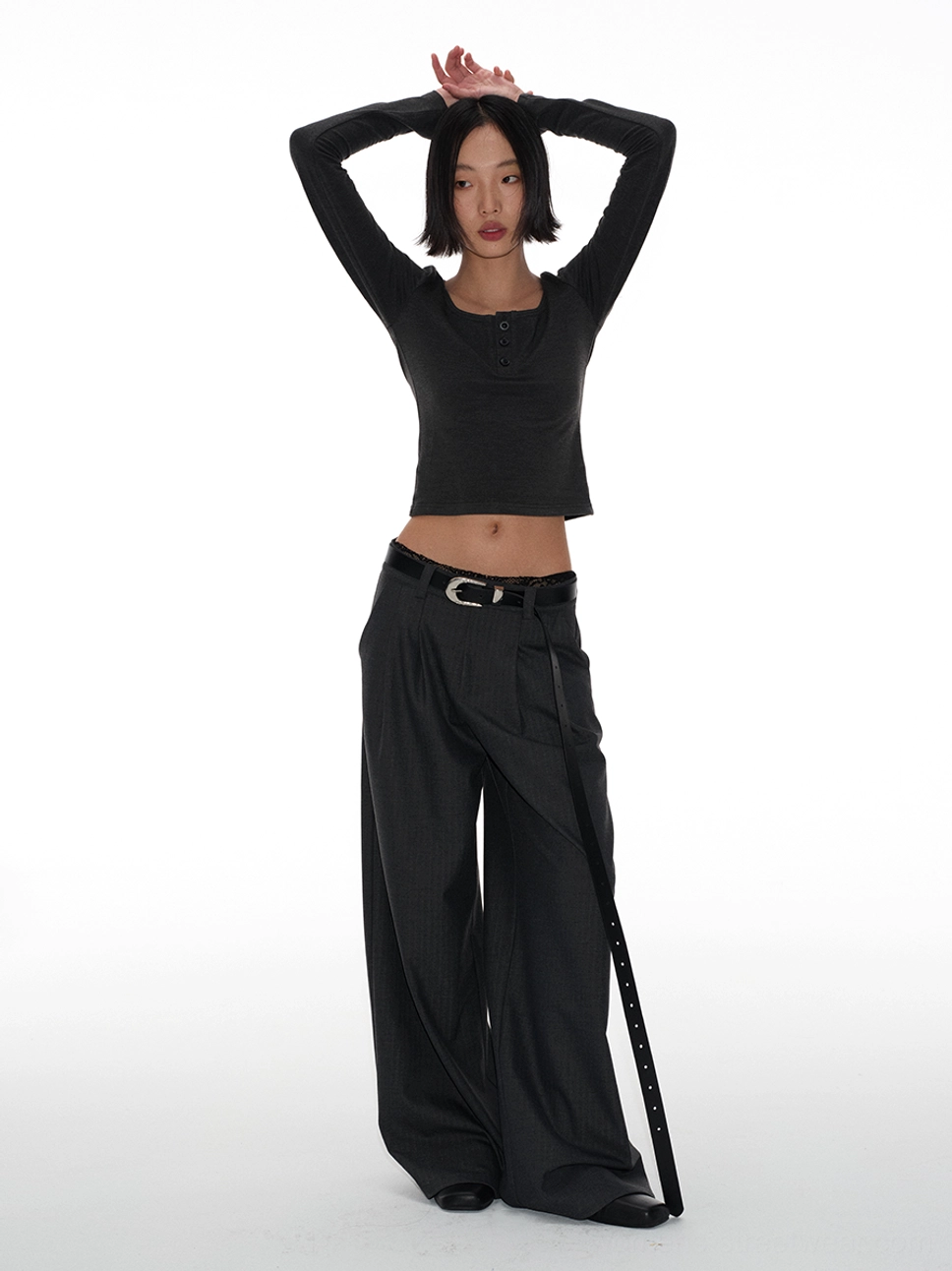 Side rear view of high-waisted belted tailored trousers with an extra-long belt strap and relaxed floor-skimming wide-leg silhouette