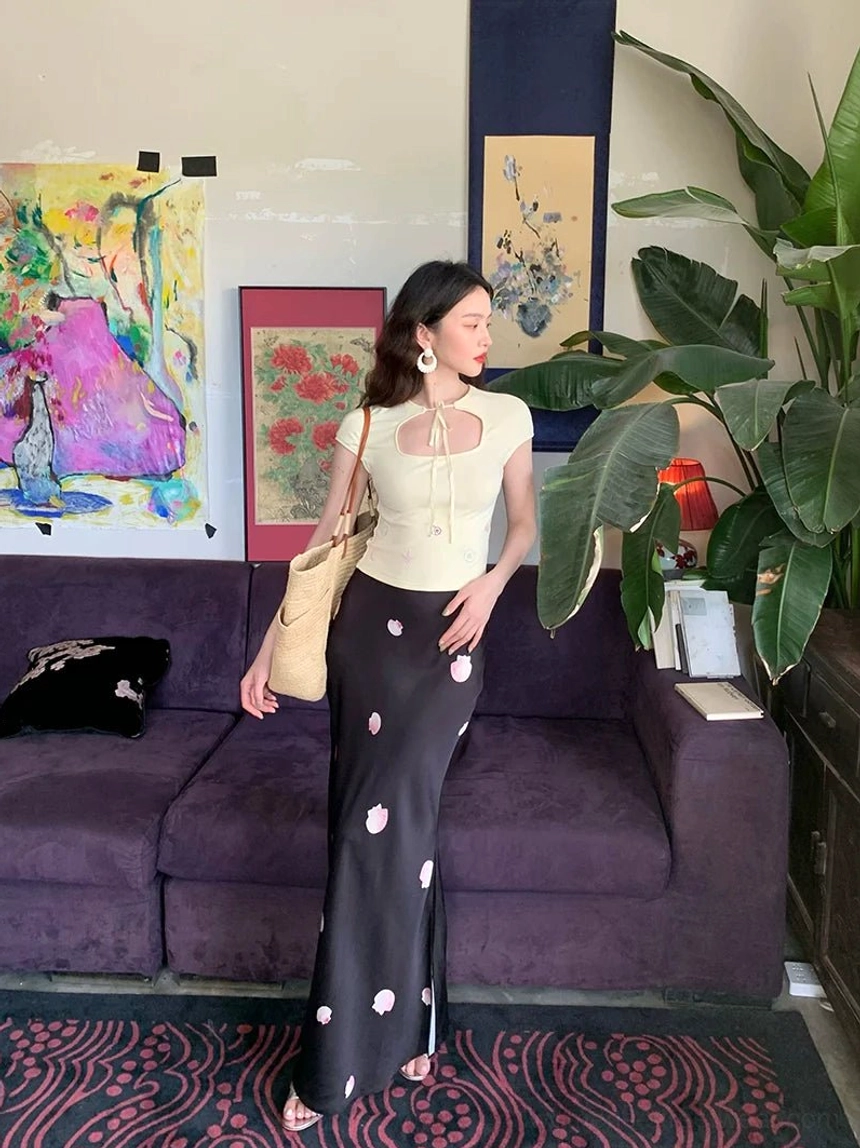 Side full-body view of a high-waisted black floral maxi skirt with ankle-skimming length and elegant flared silhouette
