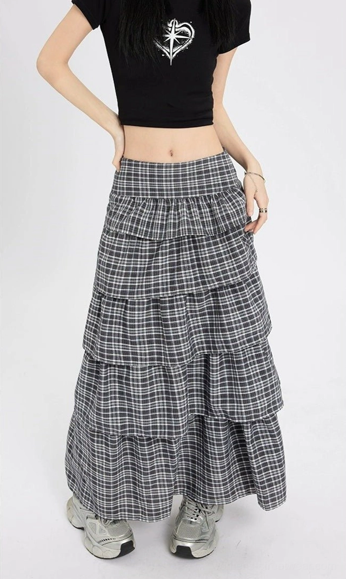 Front view of a high waisted black plaid tiered maxi skirt with flowing ruffled layers styled for Korean street fashion