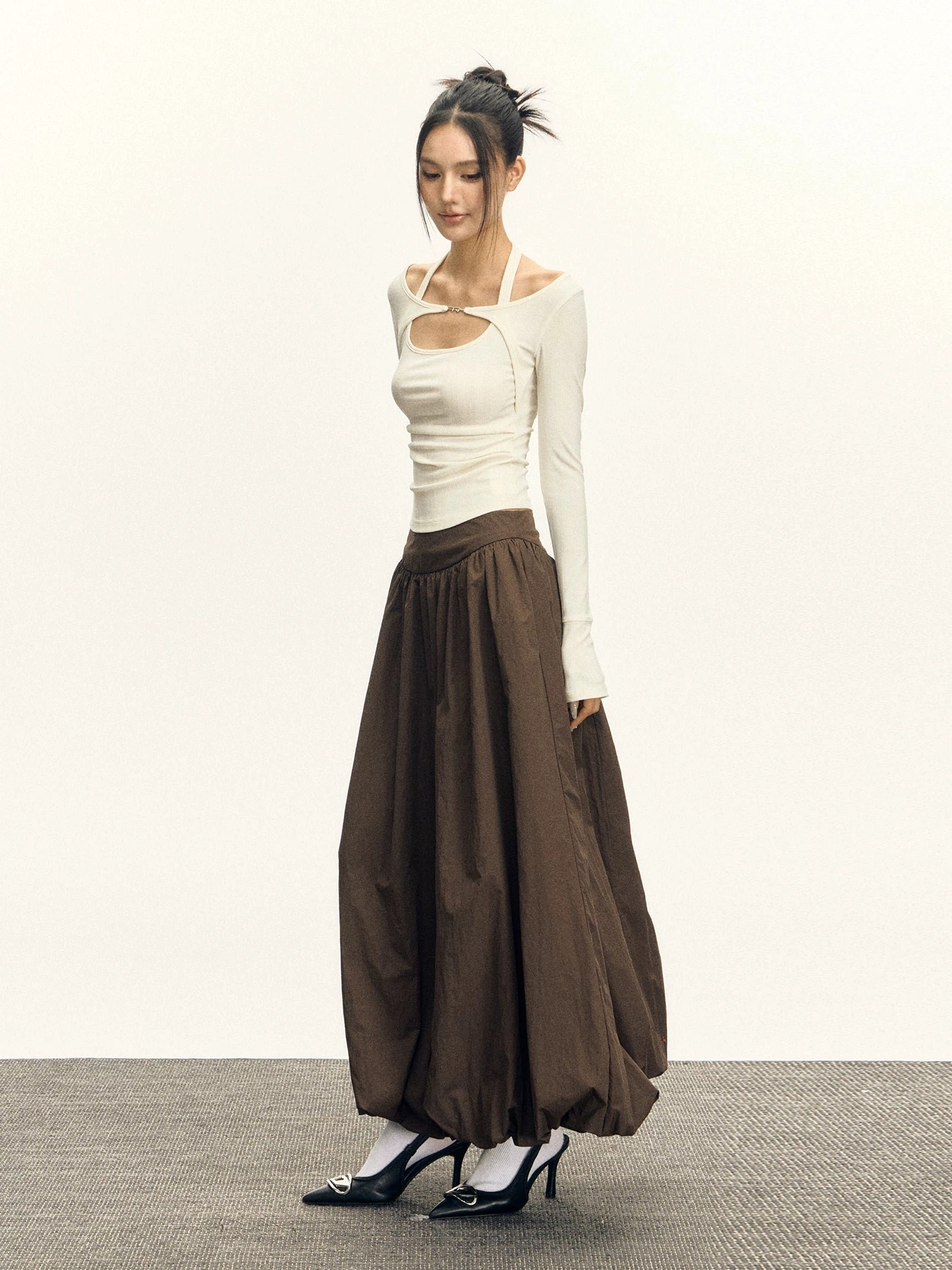 Voluminous high waisted bubble maxi skirt side profile styled with white cutout long sleeve top
