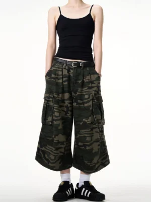 Women's high-waisted camouflage cargo culottes shown from the front with pleated waist, wide cropped legs, and hands in pockets