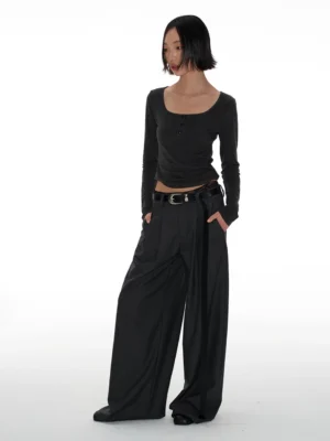 Three-quarter view of high-waisted charcoal gray streetwear pants with relaxed wide legs, front pleats, belt loops, and side pockets