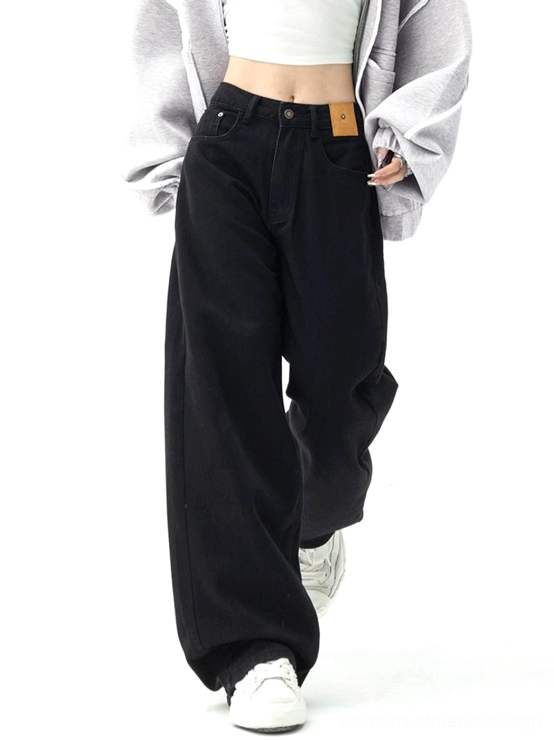 Dark blue high-waisted wide-leg denim jeans styled with a cropped white tank top, oversized gray coat, and white sneakers in a modern women's streetwear outfit