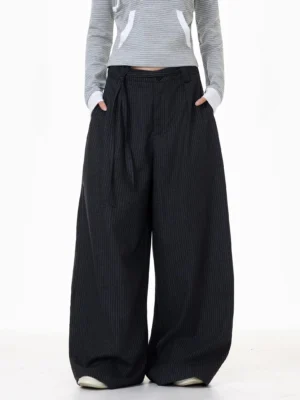 Front view of high-waisted dark gray pinstripe trousers with pleats, button fly, wide legs, and practical pockets