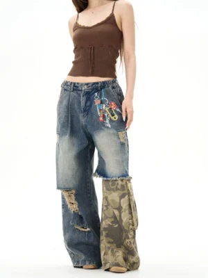 Front view of high-waisted distressed patchwork wide-leg jeans on a female model, featuring vintage washed denim, camo lower-leg panels, ripped details, and streetwear pocket embellishments