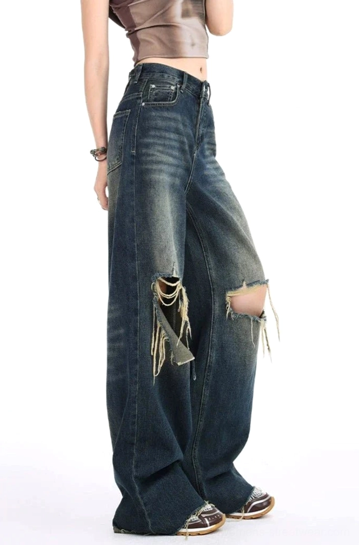 Left rear view of high-waisted distressed dark wash wide leg jeans with frayed thigh and knee rips, vintage denim texture, cropped top, and leather streetwear shoes
