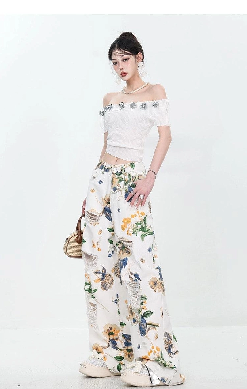 Front three-quarter styling view of high-waisted floral distressed denim jeans with chunky sneakers