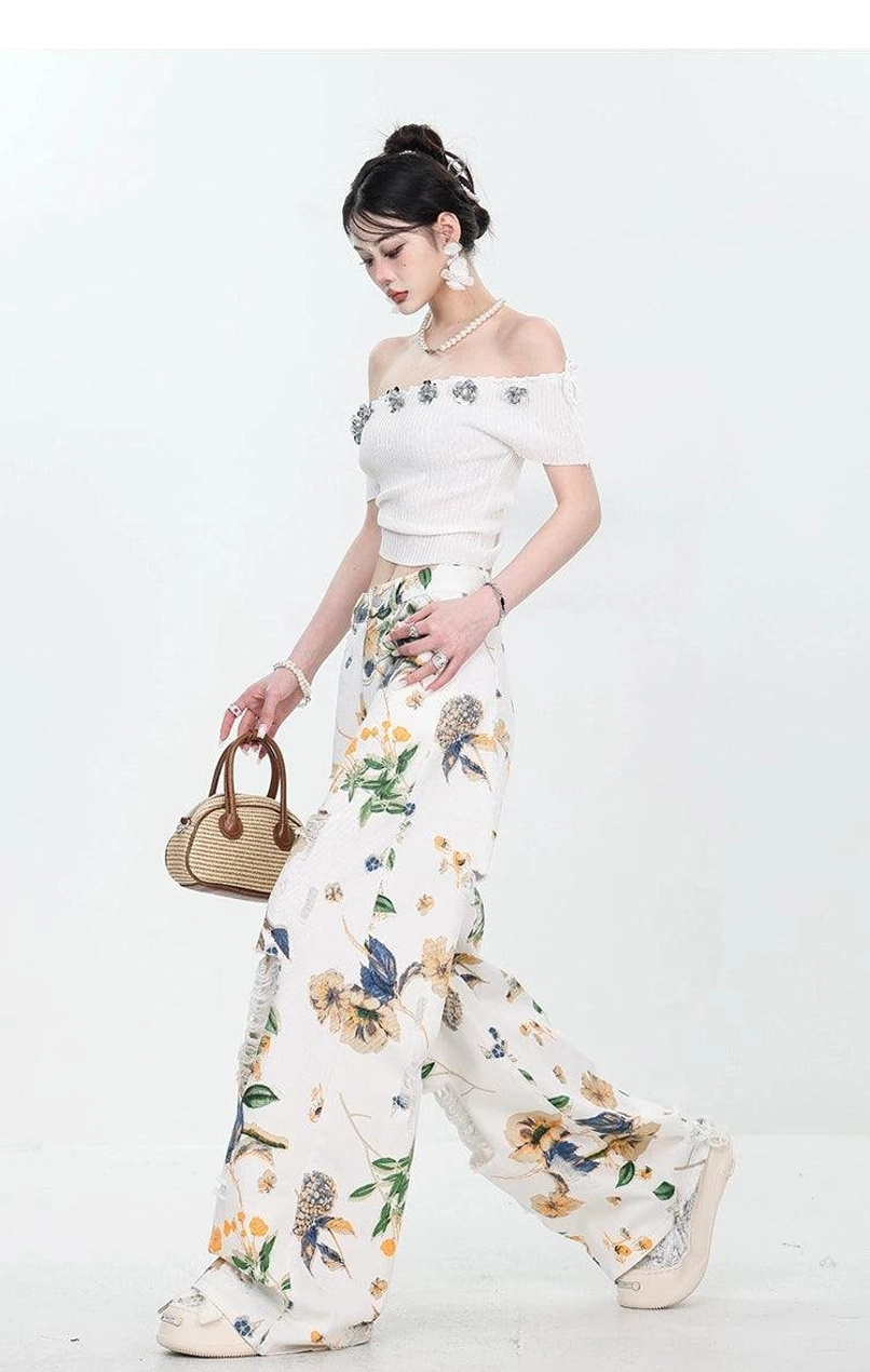 Side walking view of high-waisted floral print wide-leg jeans with distressed denim details