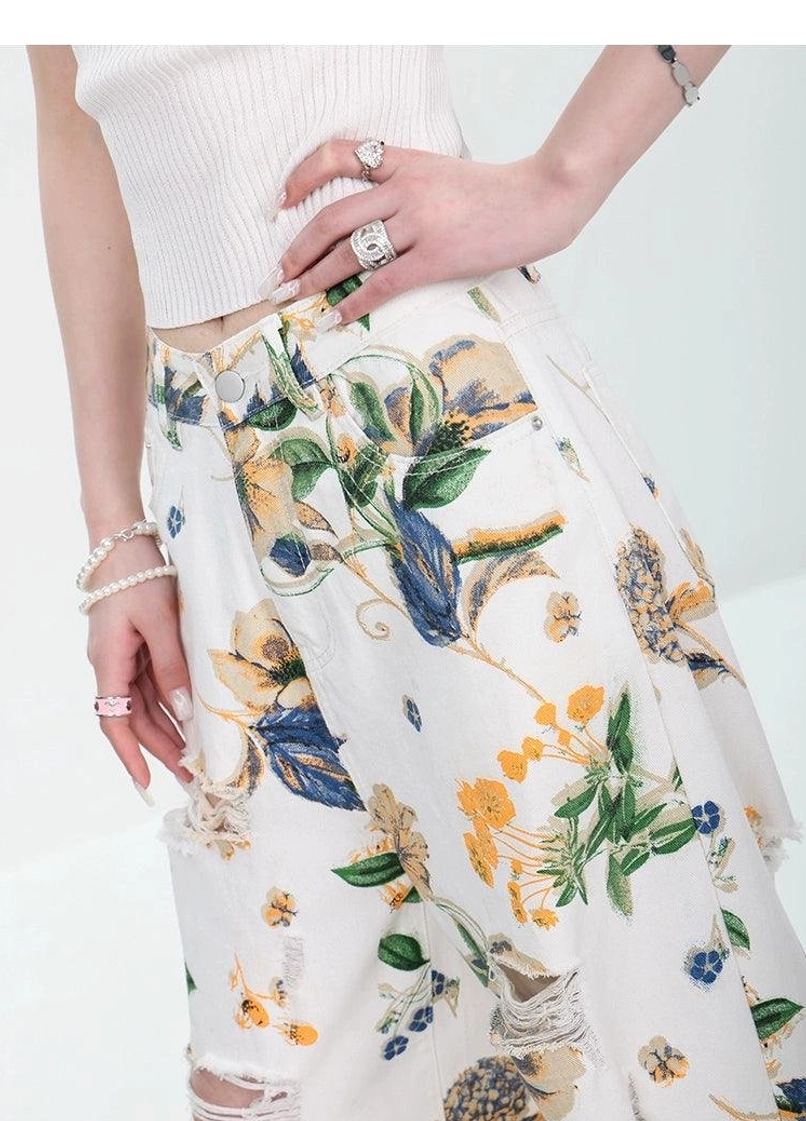 High-waisted statement denim jeans with floral print, wide legs, and modern distressed detailing