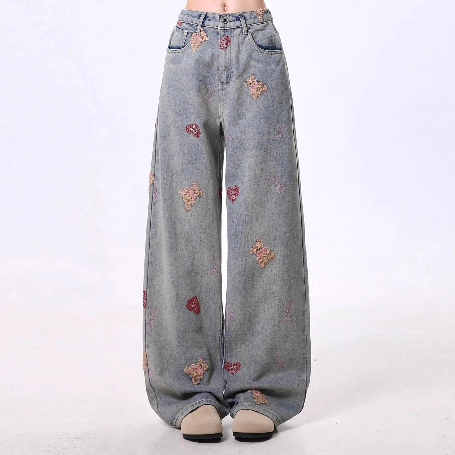 Front view of high-waisted teddy bear embroidered wide-leg jeans showing button fly, belt loops, vintage wash, and cute heart details