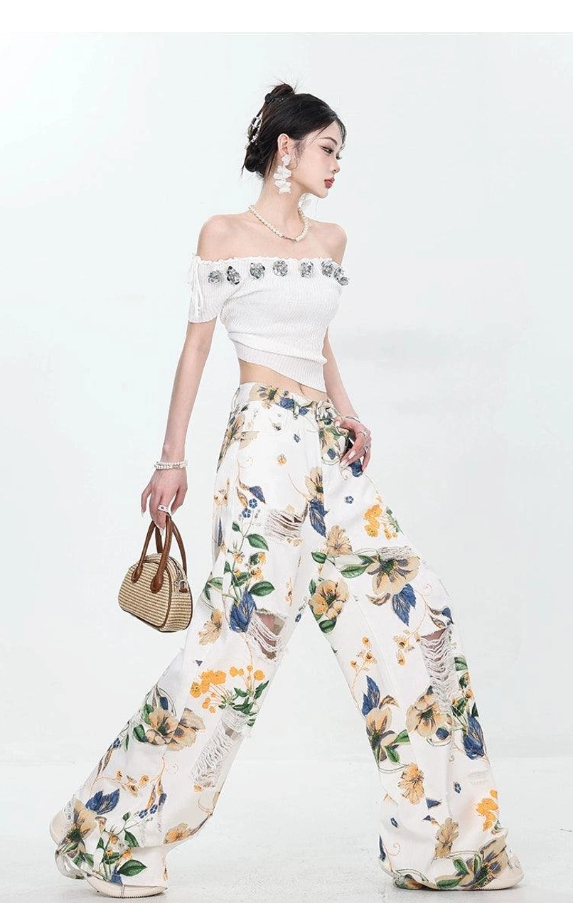 High-waisted women's wide-leg jeans featuring vintage-inspired floral pattern and distressed accents