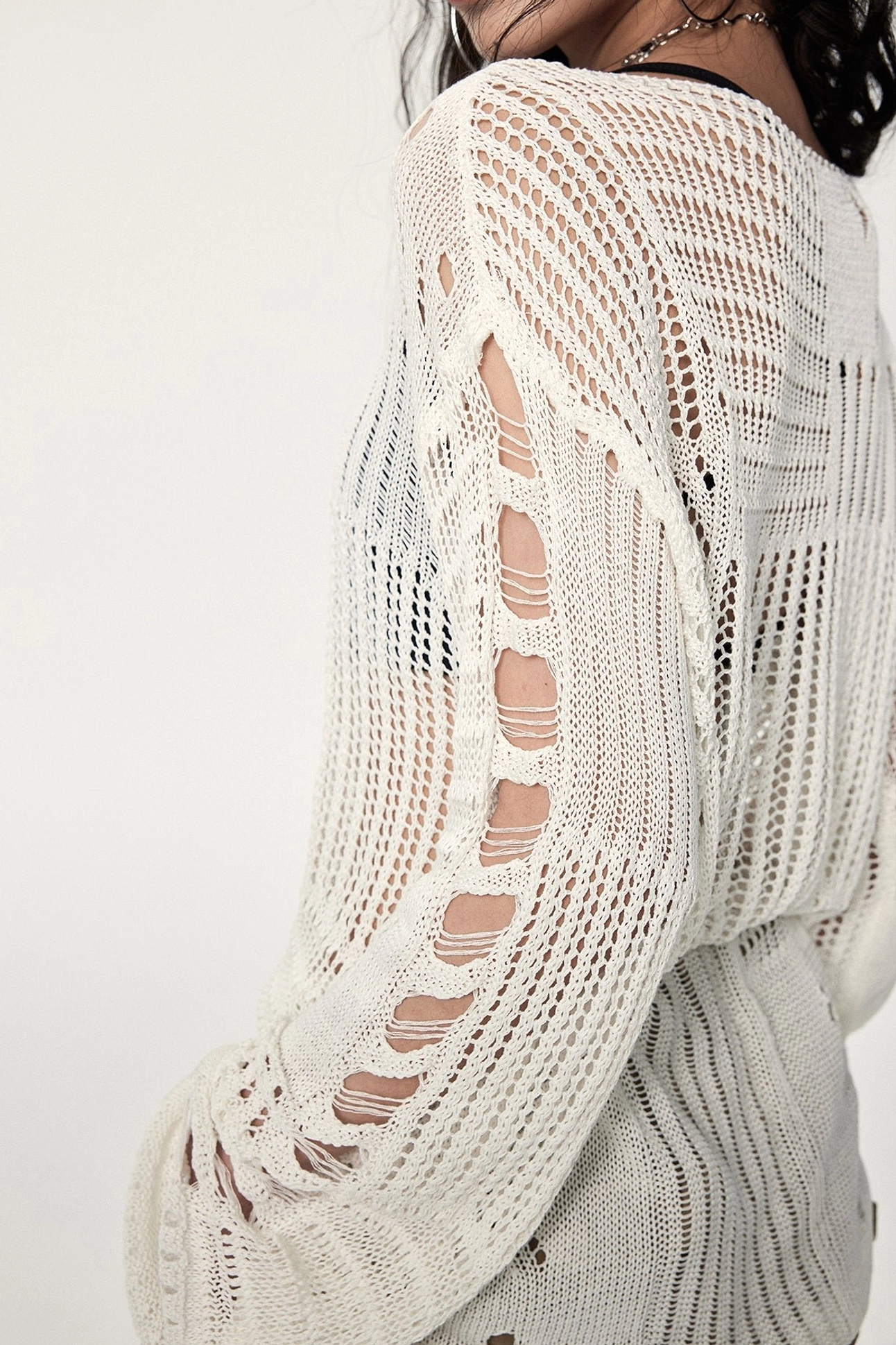 Hollow-out distressed crochet knit sweater in a versatile off-white color with industrial metal ring accents and deconstructed silhouette