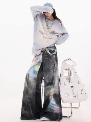 Back three-quarter view of holographic gradient wide-leg jeans styled with a distressed cropped sweater, denim baseball cap, and white leather tote bag