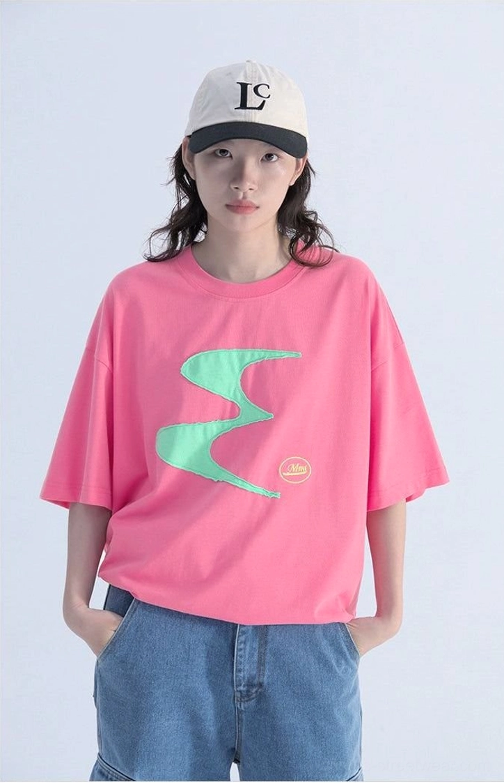 Close-up front view of a hot pink oversized streetwear tee with mint green irregular wavy graphic, relaxed drop shoulders, and crew neckline