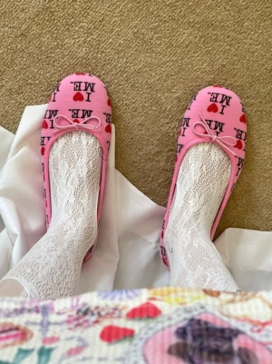 Pink I Love Me graphic ballet flats with bow detail styled with white lace ankle socks in top view