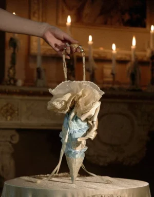 Ice blue cone drawstring handbag with ivory ruffled lace trim and satin ribbon bow on vintage table