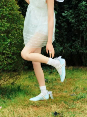 Ice-blue rhinestone Mary Jane flats worn with a sheer white mini dress and ruffled socks in a dreamy garden streetwear outfit