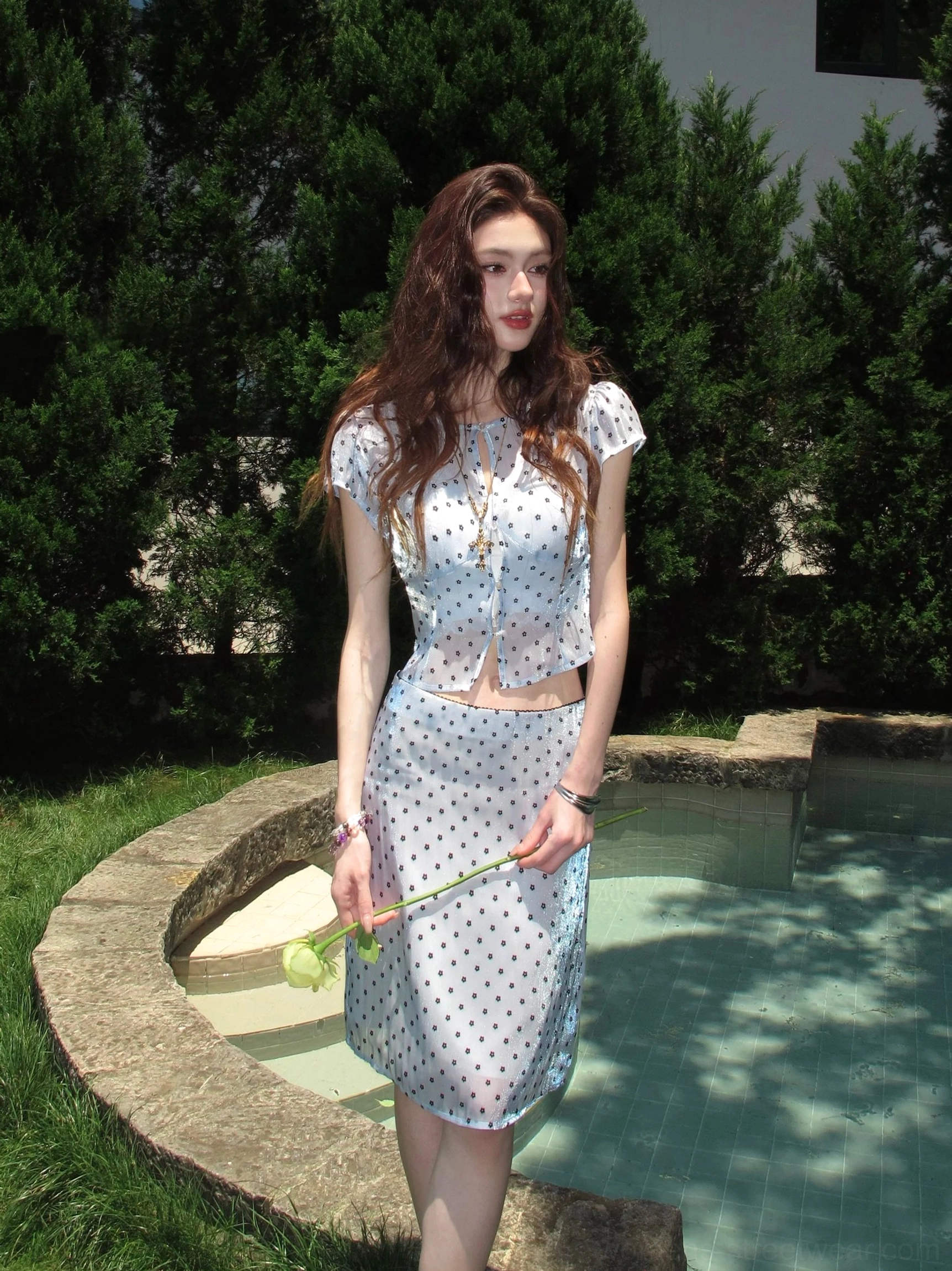 Light blue sheer polka dot cropped blouse and matching high waist skirt styled with yellow rose by pool