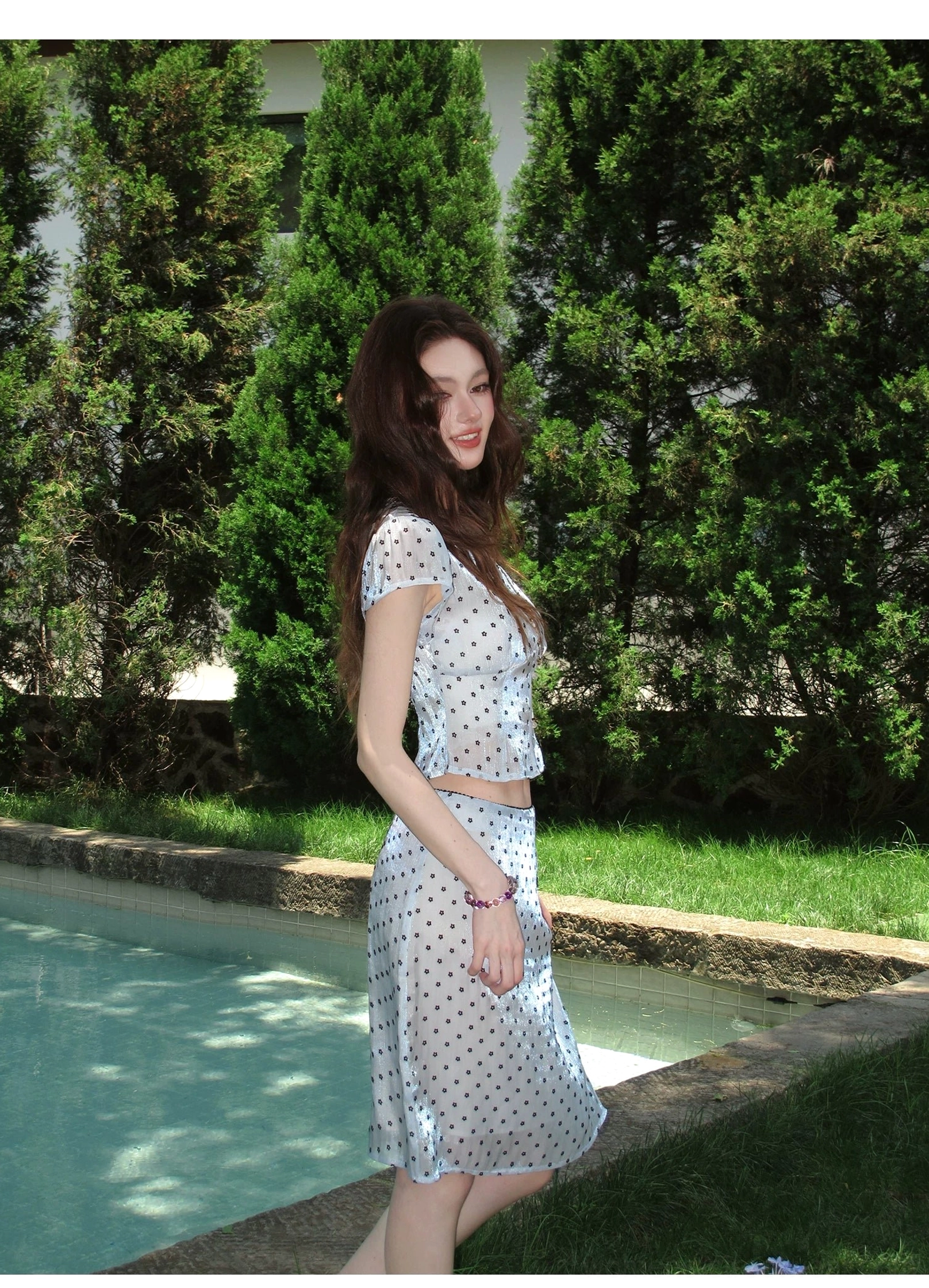 Side view of light blue sheer polka dot cropped top and high waist skirt two piece streetwear outfit