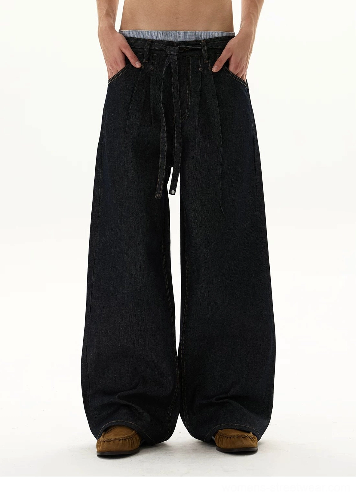 Front close styling view of oversized indigo balloon jeans with visible tie waist, relaxed pleated upper leg, and ultra-wide denim silhouette