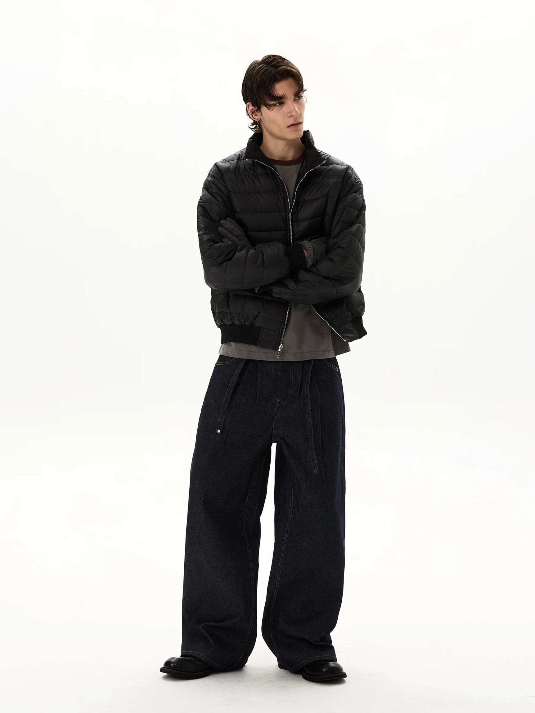 Full-body styling view of oversized indigo streetwear jeans with exaggerated wide legs worn with a black puffer jacket