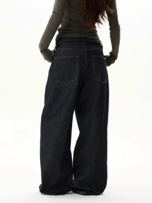 Rear view of oversized dark indigo wide-leg jeans showing classic back pockets, contrast stitching, relaxed balloon fit, and tie waist detail