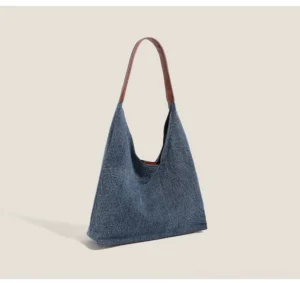Indigo denim hobo bag shown from a three-quarter angle with curved opening and textured fabric body