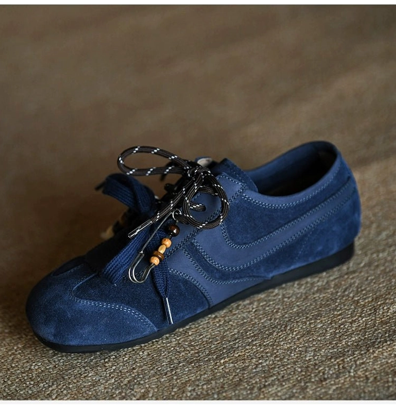 Angled view of an indigo suede streetwear sneaker featuring mixed metal wire and bead lace decorations