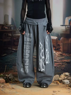 Heather gray Inferno Glyph gothic wide leg streetwear pants with white flame graphic, vertical text print, layered front drape, and side waist strap