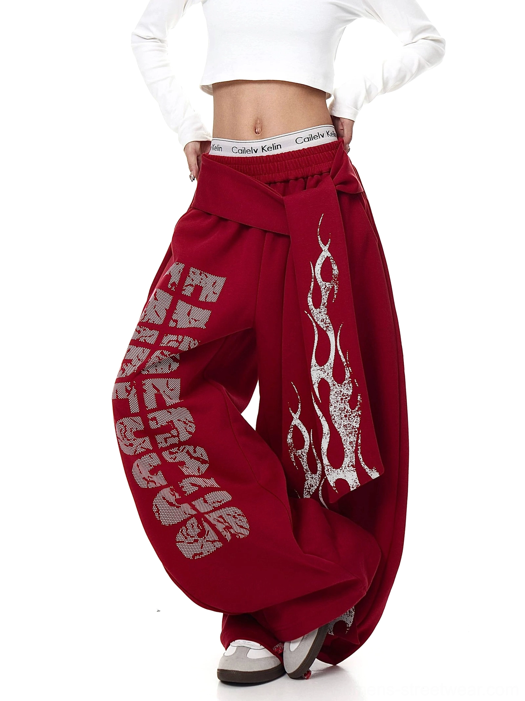 Front three-quarter view of burgundy wide-leg streetwear sweatpants featuring distressed graphics and flame print