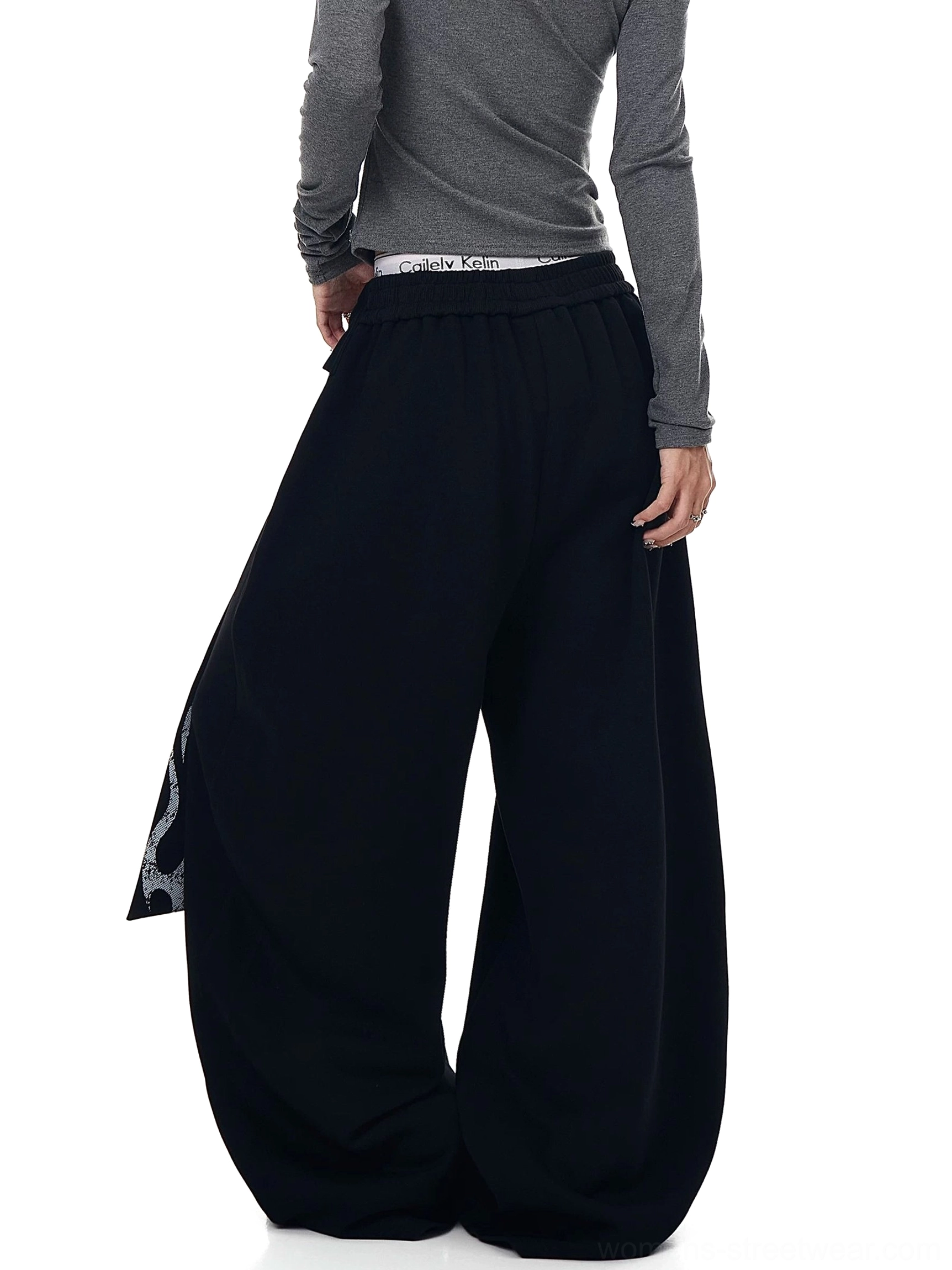 Back view of dark gray oversized fleece sweatpants with relaxed wide-leg silhouette and draped side waist detail