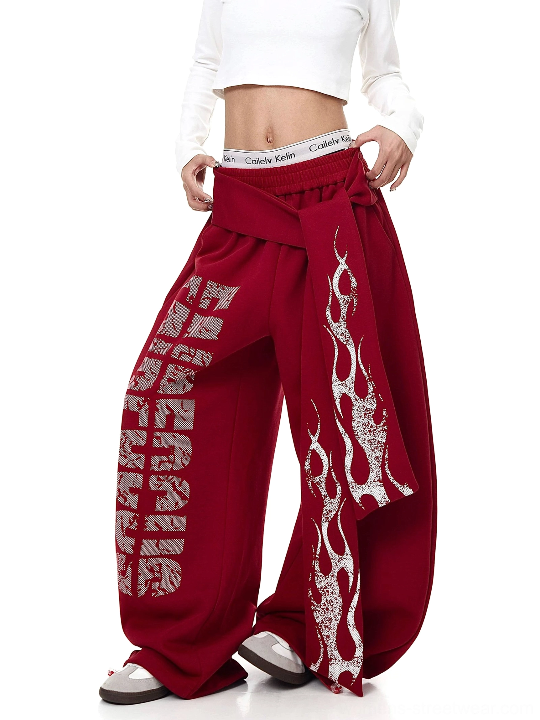 Side three-quarter view of red flame graphic wide-leg fleece sweatpants with long asymmetric waist wrap