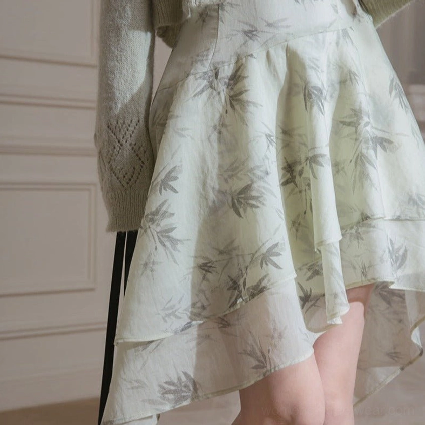 Close up of flowing ink bamboo print chiffon dress with layered asymmetric ruffle hem and grey ribbed cardigan
