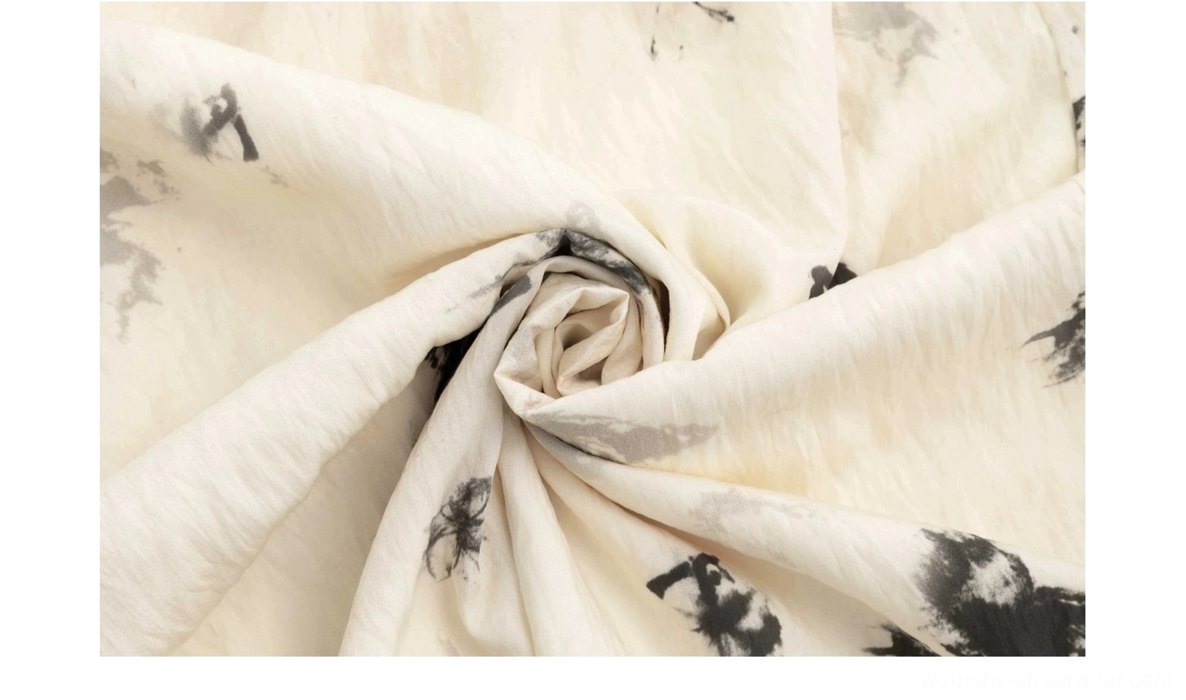 Close-up of cream crinkled micro-pleated fabric with black ink butterfly print
