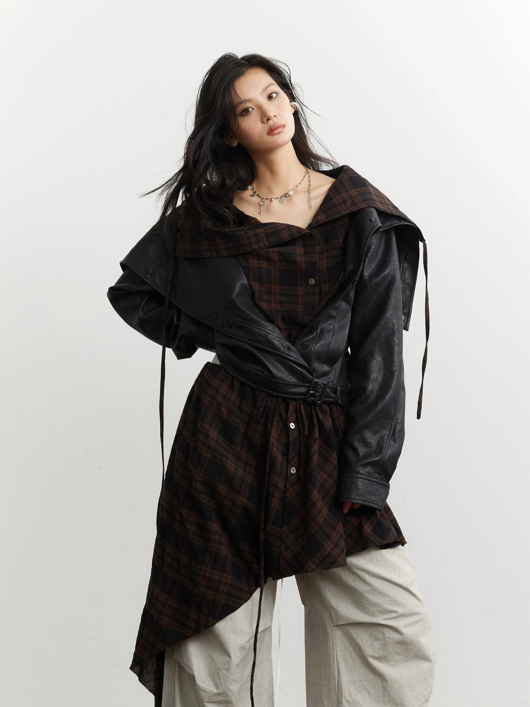 Front three-quarter view of an integrated black faux leather and tartan plaid cropped jacket with tied wrap waist styling