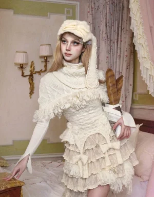 Ivory cable knit fringe shrug styled over a romantic layered ruffle skirt in a vintage-inspired streetwear outfit