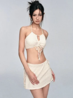 Side three-quarter view of an ivory crochet bikini and matching mini skirt with adjustable side ties