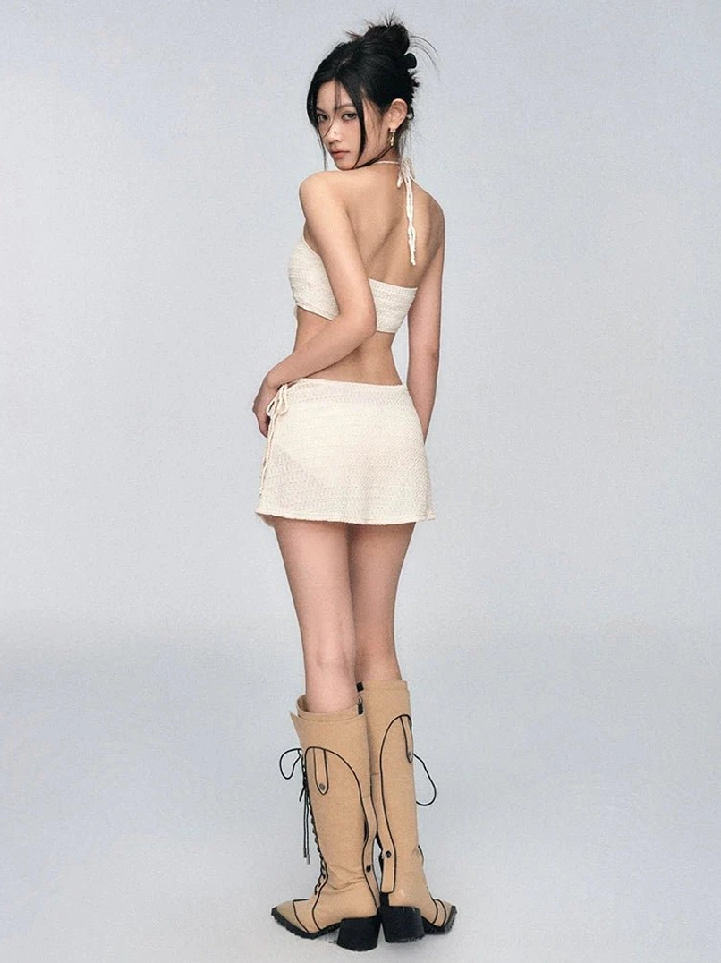 Back view of an ivory crochet halter bikini set showing the exposed back tie and textured mini skirt