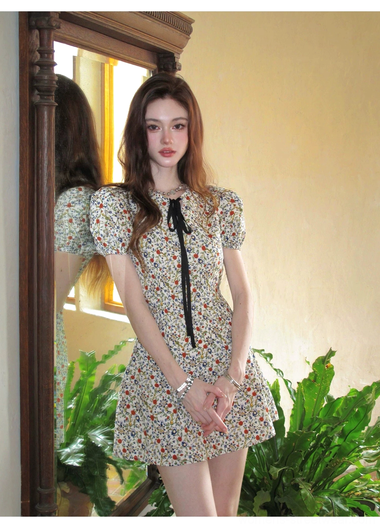 Close mirror view of the black ribbon bow neckline on an ivory ditsy floral puff sleeve mini dress