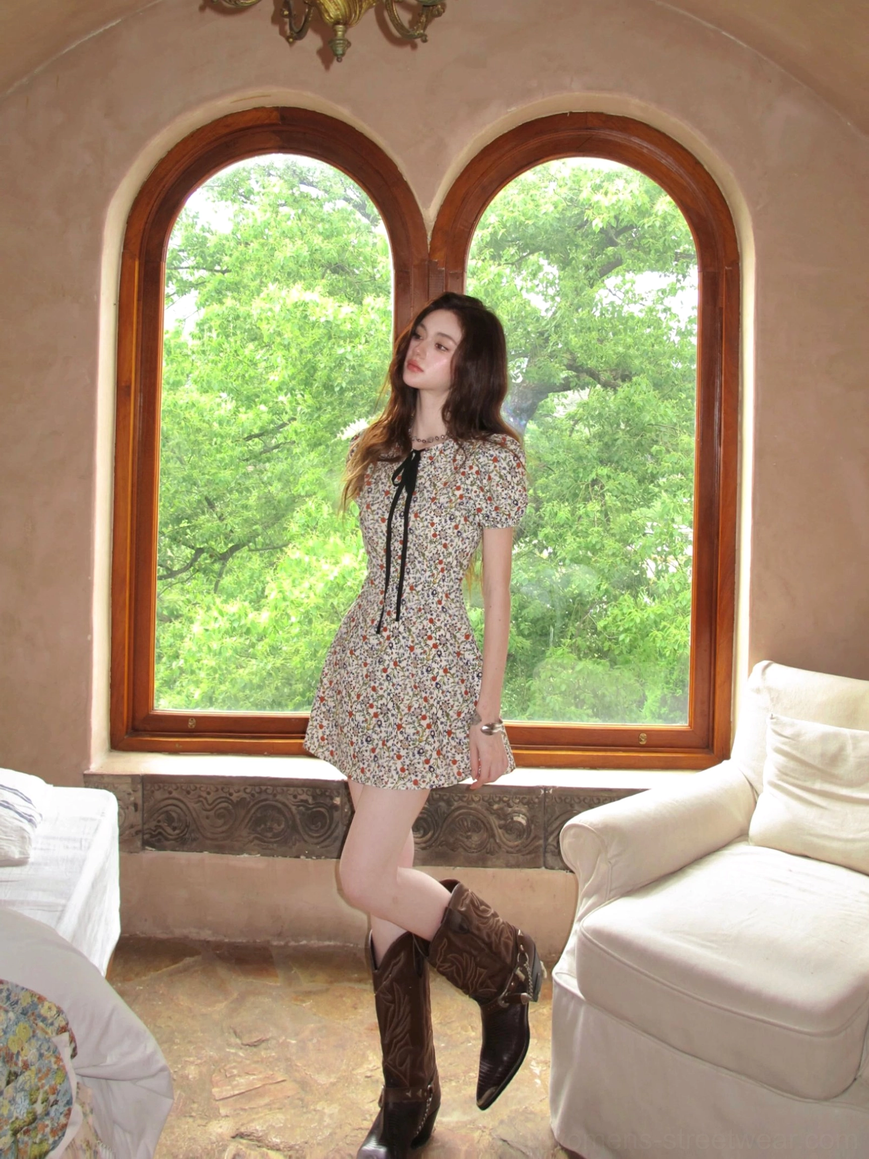 Three-quarter side view of ivory floral bow-tie puff sleeve mini dress styled with brown cowboy boots