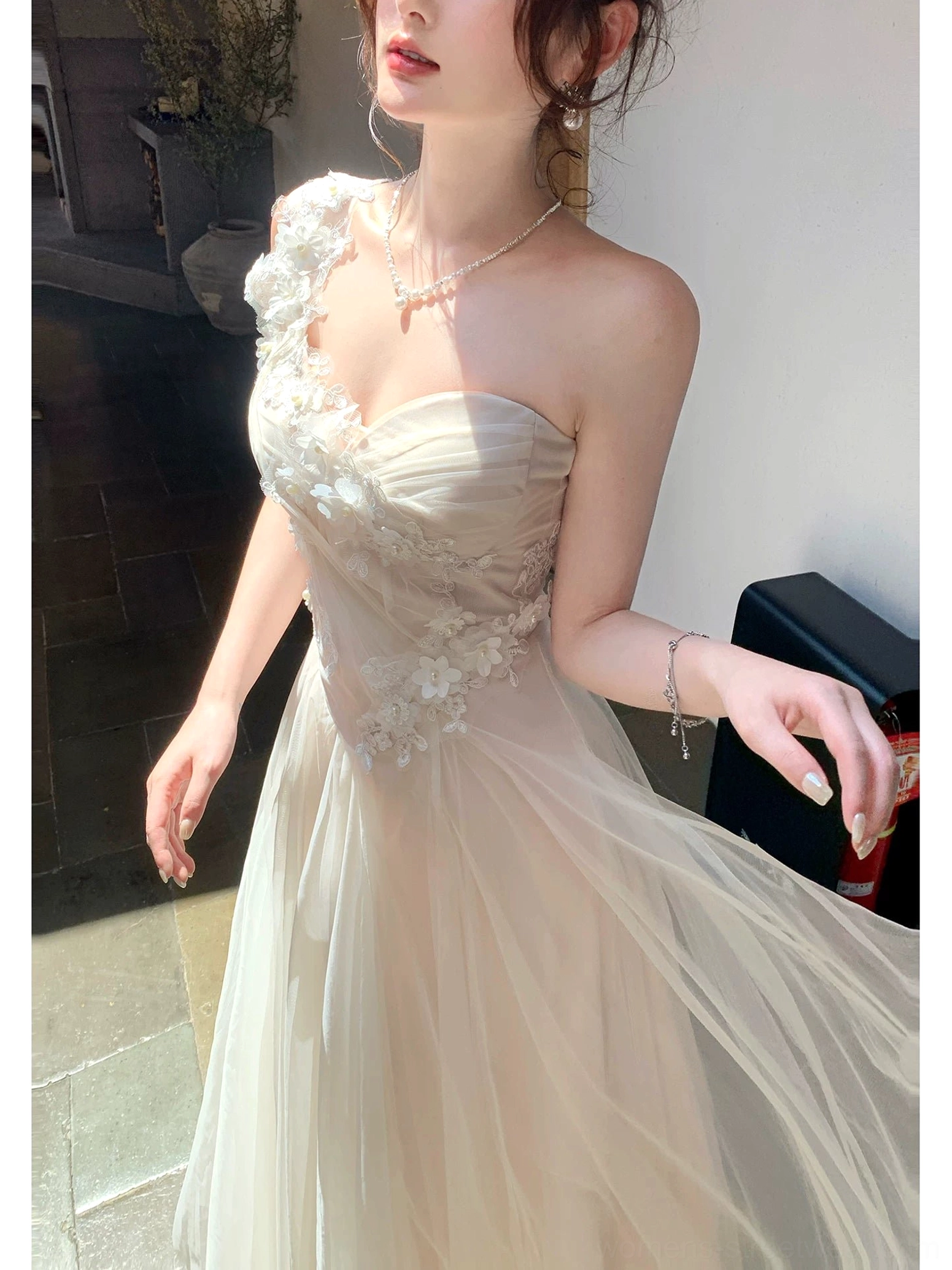 Close-up of the ivory floral embroidered tulle maxi dress neckline and bodice showing the asymmetrical one-shoulder design, raised floral details, and lightweight fabric