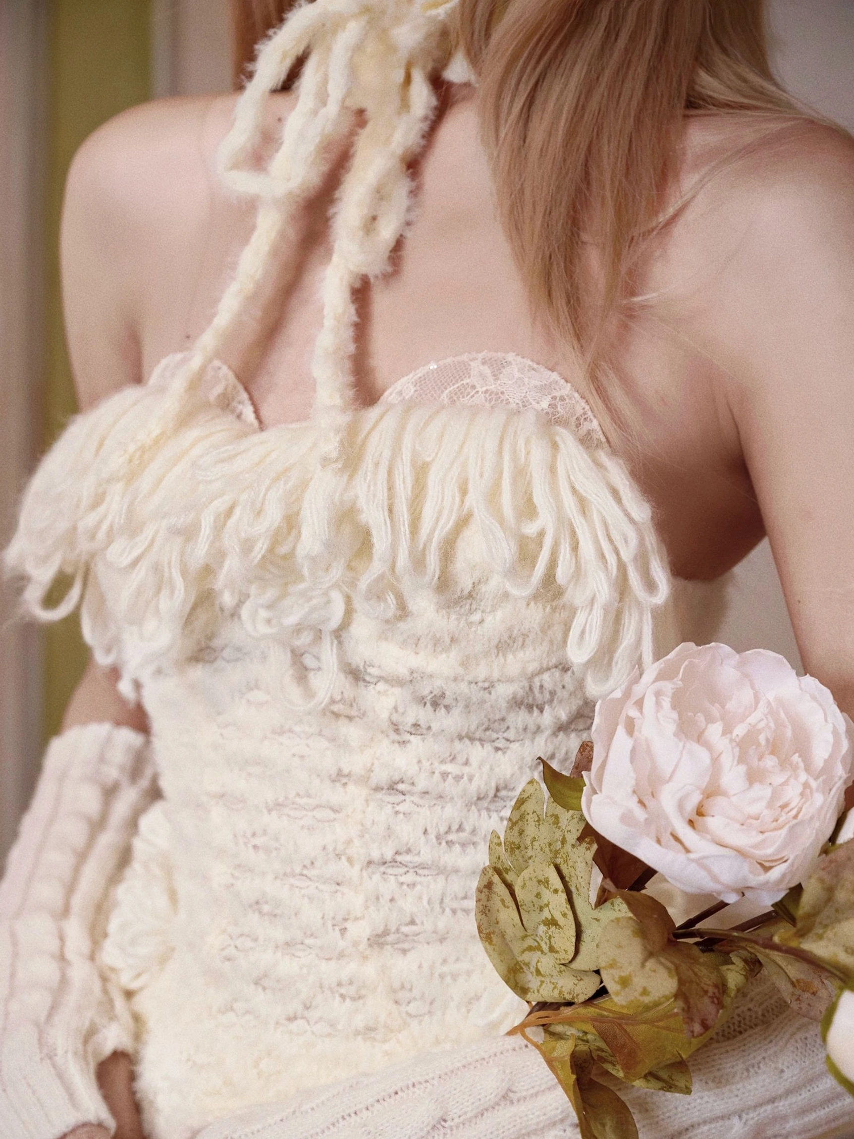 Close-up of ivory fringe knit corset top with textured bust detailing, lace trim, halter styling, and matching knit gloves