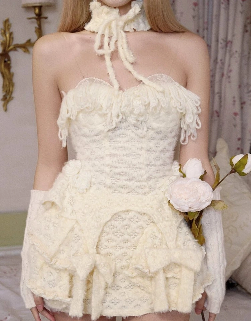 Close-up front view of ivory fringe knit corset top with halter tie, frayed tassel fringe, and gathered knit texture