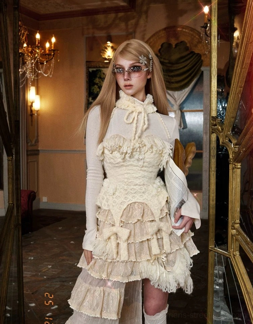 Ivory fringe knit corset top product detail view featuring plush fringe, knit rosette accents, and garter-inspired lower panels
